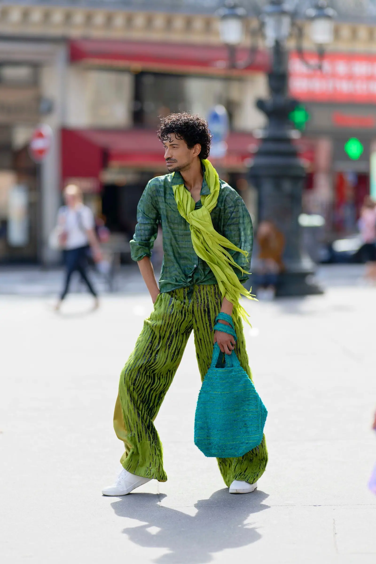 Marlon crossing a Paris street in a green pleated look with a teal bag