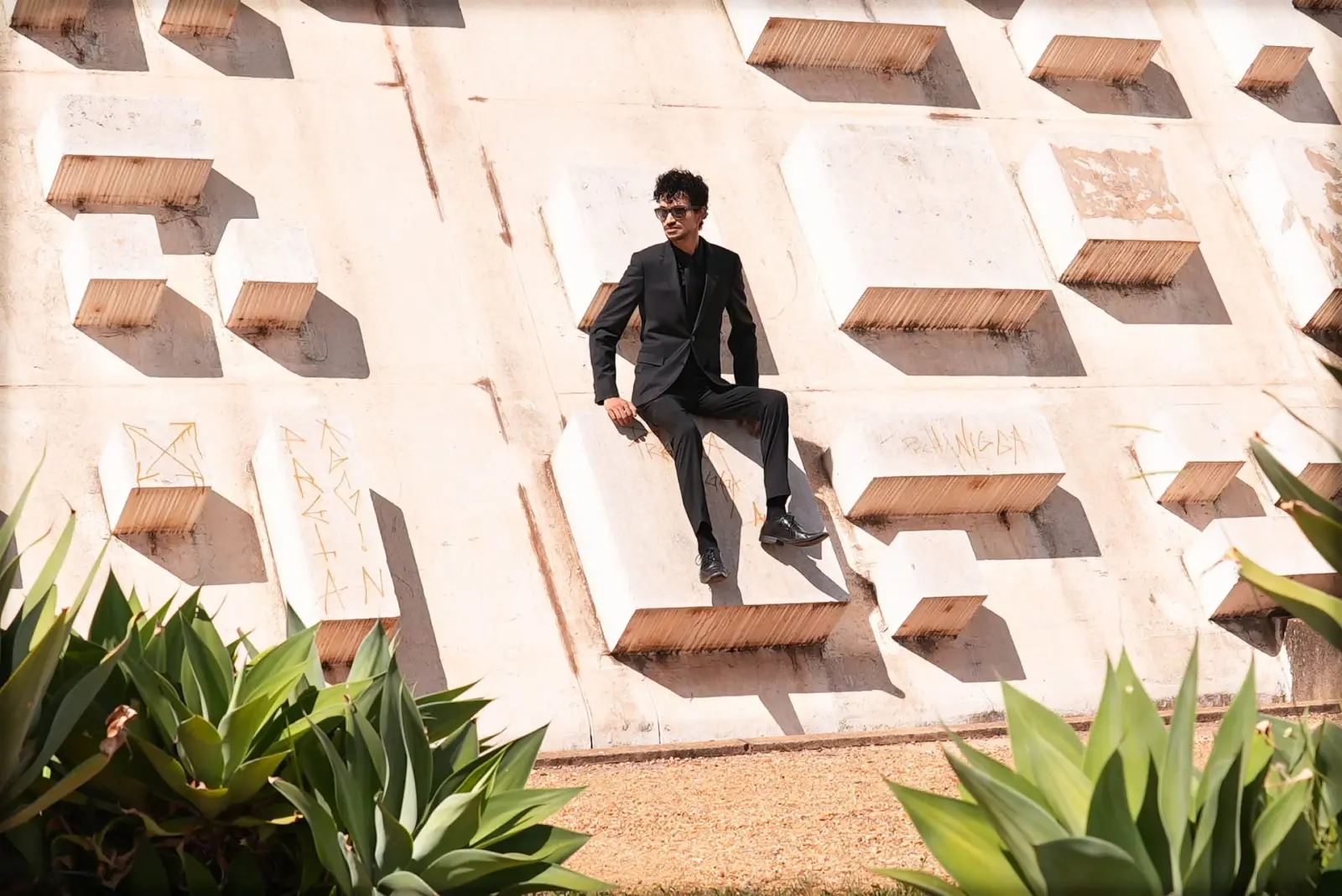 Marlon perched on a sculpted facade among agave plants
