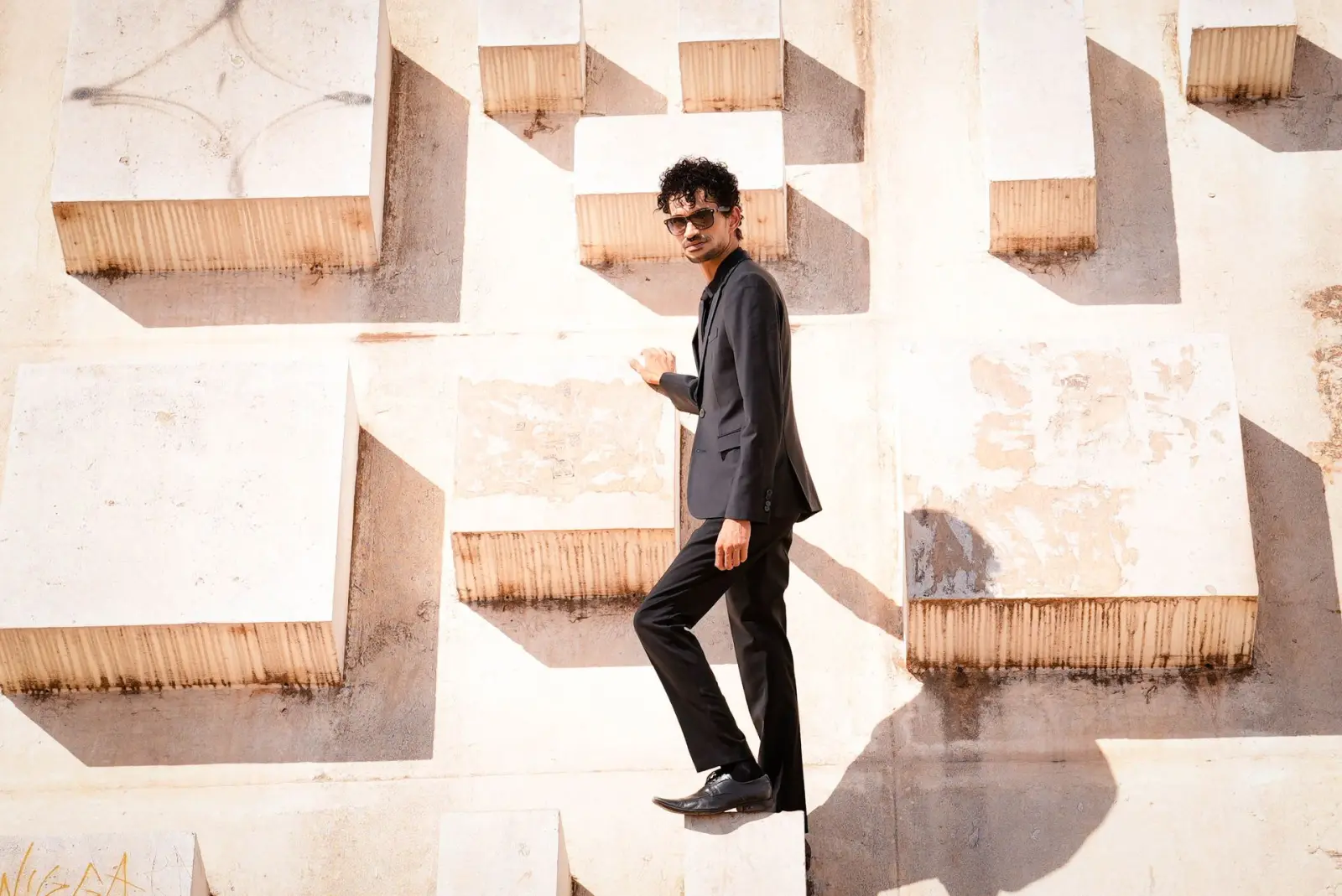 Marlon in black, mid-stride across a sculpted white facade