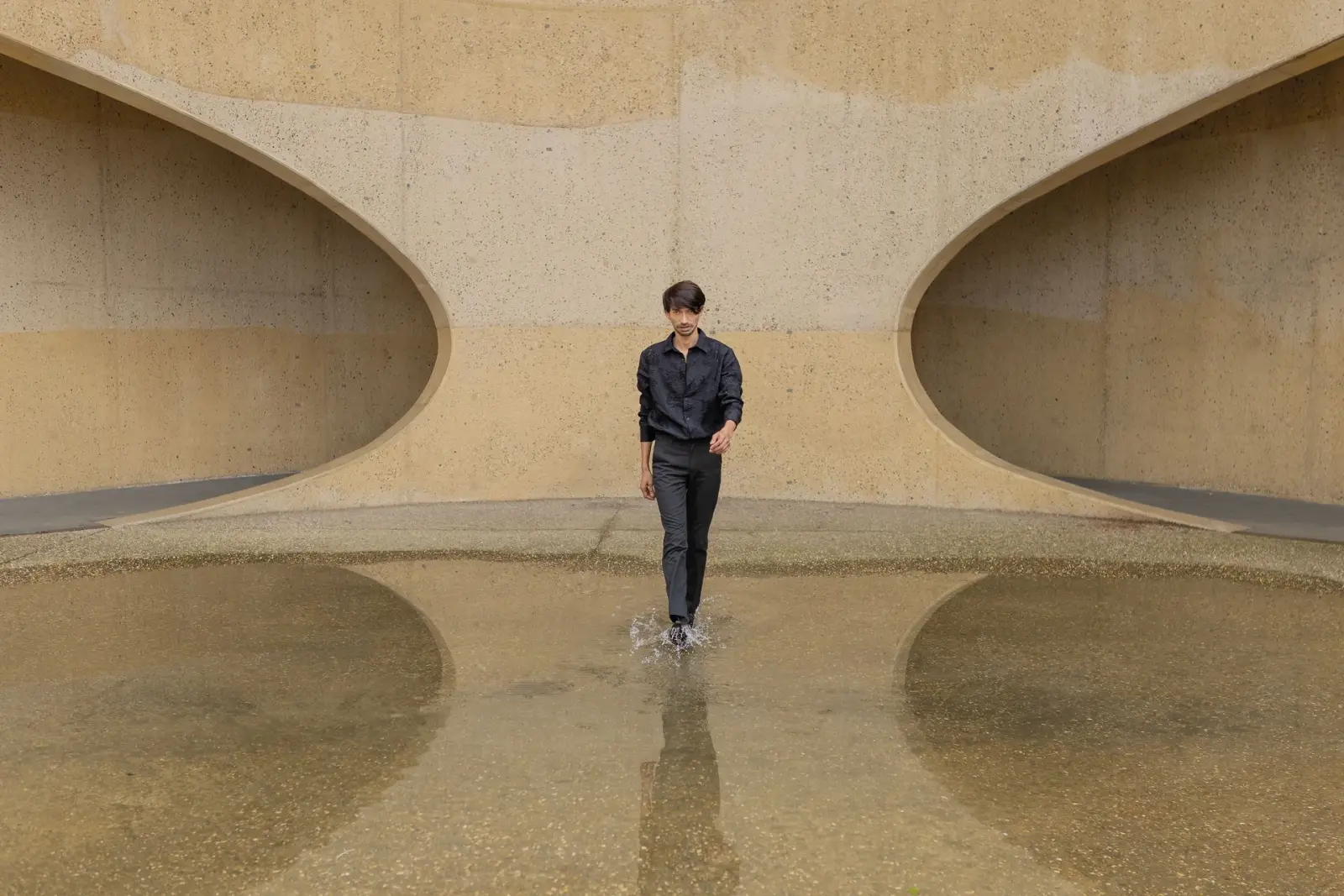 Marlon standing in shallow water beneath a sweeping concrete arch